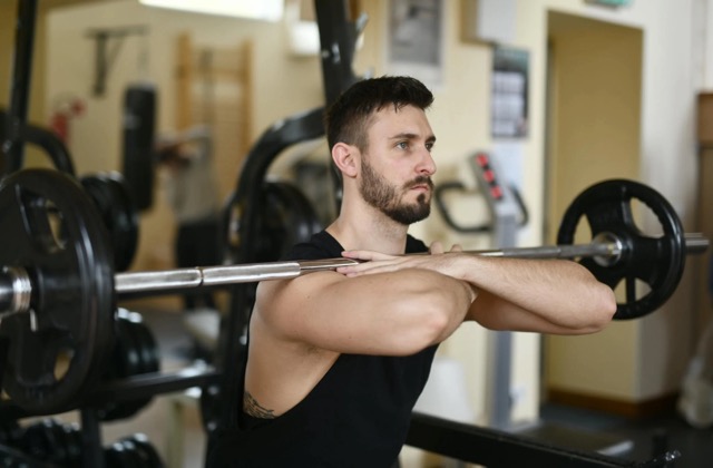 Man performing a front squat with proper upright torso positioning to reduce forward lean during barbell squats.