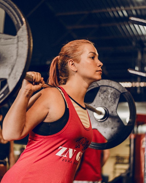 Woman performing barbell back squat with upright torso, demonstrating proper squat technique