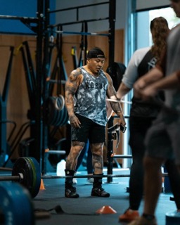 A muscular man prepares to deadlift in a gym, focusing intently before the lift